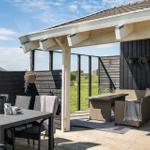 Terrace with seating and table under roof. Black wooden walls and hanging flowers.
