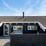 Black house with wooden porch and tiled roof. House number 30.