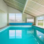 Indoor pool with blue water and large windows for views.