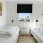 Two beds with white bedding are under a window with a view of a house.