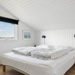 Bedroom with double bed, window, and white walls.