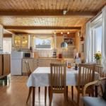 Dining room with wooden floor, table with chairs, and kitchen area in the background.