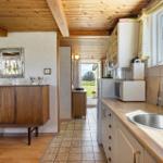 Kitchen with worktop, sink, and kitchen cabinets. Wooden ceiling and sideboard in background.