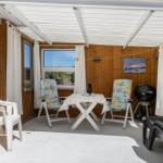 Patio with table, two chairs, grill, and lounge chairs under roof.