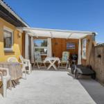 Terrace with table, chairs, sun loungers, and grill under awning.