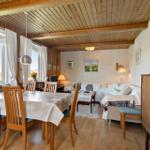 Dining room with table and chairs. Living area with sofa and coffee table. Wooden ceiling and windows with view.
