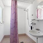 Bathroom with shower, sink, and mirror. Shower curtain with fish pattern.