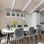 Dining area with white table, gray chairs, and kitchen with white cabinets.