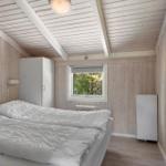 Bedroom with wooden paneling, bed, and window to greenery.