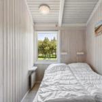 Bedroom with bed, window, and wood paneling.