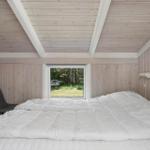 Bedroom with bed, window, and chair. Wooden walls and ceiling.