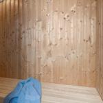 Sauna with wooden walls and bench, blue towel, and wall clock
