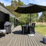 Deck with table, chairs, and umbrella. Grill and bench beside house wall.