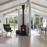 Living and dining area with fireplace, glass doors, and wooden floor.