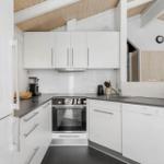 Modern kitchen with white cabinets, stainless steel appliances, and dark countertops.