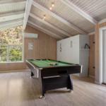 Room with pool table, wooden walls, and windows to nature.