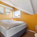 Bedroom with bed, wall art, and window. Wooden walls and white ceiling beams.