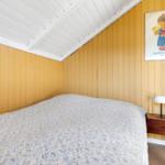 Bedroom with yellow panel wall, bed, and nightstand with lamp.