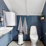 Bathroom with blue walls, toilet, sink, and mirror