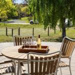 Round table with chairs and wine on terrace overlooking green area and trees.