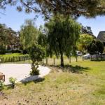 Lawn area with wooden bench, trees, and blue sky.