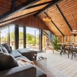 Living and dining area with wooden ceiling, large sofa, and view of the terrace.