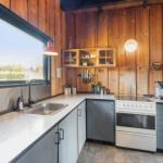 Kitchen with wooden walls, countertop, sink, stove, and window.