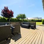 Wooden terrace with garden furniture, bench, and view of green lawn.