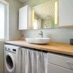 Bathroom with washing machine, sink, and mirror. Window with two rubber ducks.