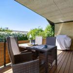 Terrace with garden furniture, table, and view of green hedge.