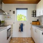 Kitchen with white cabinets, stainless steel sink, and window overlooking trees.