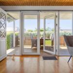 Bright terrace with table and chairs. Wooden floor and white sliding doors.