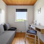 A room with sofa, desk and window. Wooden ceiling and floor.