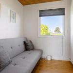 A room with gray sofa, window and white walls. Wooden floor and wardrobe.
