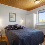 Bedroom with bed, wardrobe, and window. Wooden ceiling and floor.