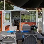 Terrace with table, chairs, and grill under awning. View into house through glass doors.