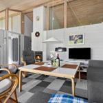 Living room with fireplace, sofa, dining table, and kitchen area in background.