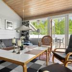 Living area with sofa, table, and chairs. Passage to terrace with view of trees.