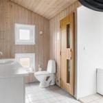 Bad mit Toilette, Waschbecken und Holzwandverkleidung.