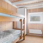 Ein Raum mit einem Doppelstockbett, Holzwand und Fenster.