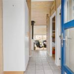 Flur mit Holzwänden, gefliestem Boden und Blick in Wohn- und Schlafzimmer.