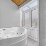 Dusche mit Whirlpool, Fenster mit getöntem Glas und Holzdecke.