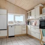 Küche mit Kühlschrank, Spülmaschine und Herd. Holzwände und Fenster mit Blick.