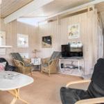 Wohnzimmer mit Holzwänden, Sofa, Stühlen und Fernseher.
