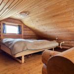 Schlafzimmer mit Holzwand, Bett und Fenster unter Dachschräge
