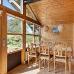 Esszimmer mit Holztisch, Stühlen und großen Fenstern zur Außenterrasse.