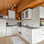 Küche mit weißen Schränken, Holzdecke und Blick in Wohnzimmer.