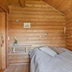 Schlafzimmer mit Holzwand, Bett und kleinem Schreibtisch.