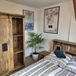 Schlafzimmer mit Holzschrank, Bett und Wandposter.