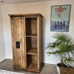 Holzschrank mit Schiebetüren, Pflanze und Poster an der Wand.